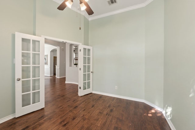 unfurnished room featuring ceiling fan, dark wood-type flooring, a towering ceiling, french doors, and crown molding