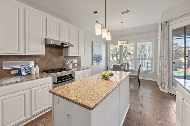 kitchen featuring decorative light fixtures, a center island, decorative backsplash, white cabinetry, and stainless steel appliances