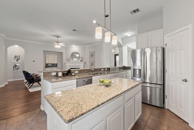 kitchen with ceiling fan, stainless steel appliances, a kitchen island, and decorative light fixtures