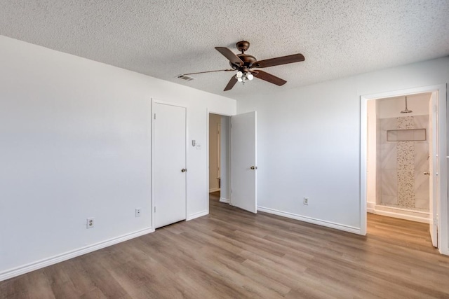 unfurnished bedroom featuring a textured ceiling, ceiling fan, connected bathroom, and light hardwood / wood-style flooring