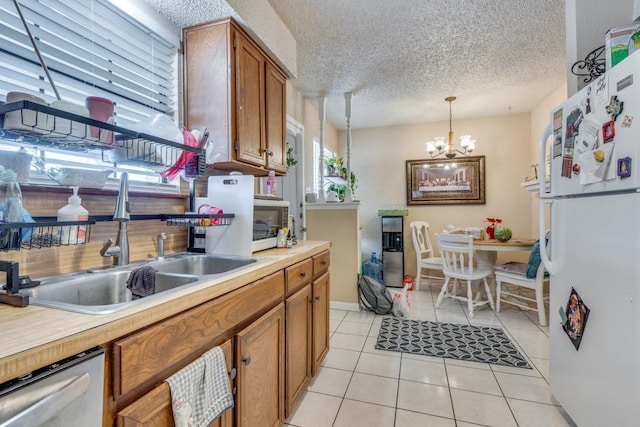 kitchen with decorative light fixtures, dishwasher, white fridge, sink, and light tile patterned floors