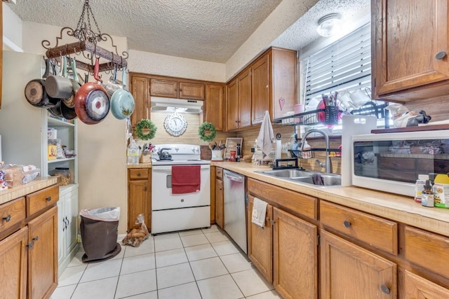 kitchen with light tile patterned floors, white appliances, hanging light fixtures, a textured ceiling, and sink