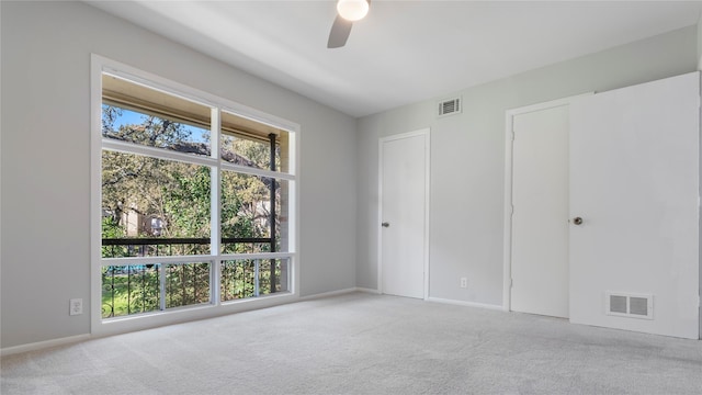 unfurnished bedroom featuring ceiling fan, light colored carpet, and multiple windows