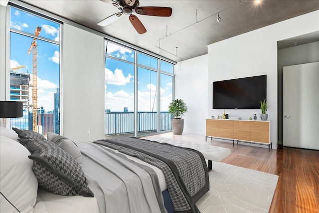 bedroom featuring ceiling fan, floor to ceiling windows, hardwood / wood-style floors, and access to outside