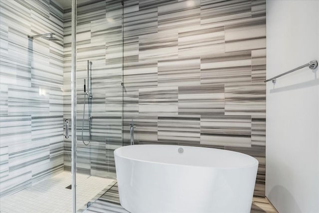 bathroom featuring plus walk in shower and tile walls