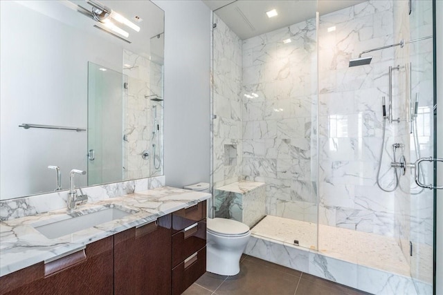 bathroom featuring a shower with shower door, vanity, tile patterned flooring, and toilet