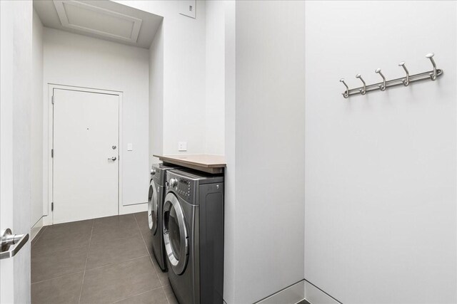 clothes washing area with washer and clothes dryer and dark tile patterned floors