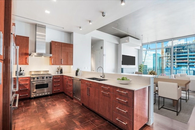 kitchen with kitchen peninsula, dark hardwood / wood-style floors, wall chimney exhaust hood, high quality appliances, and sink