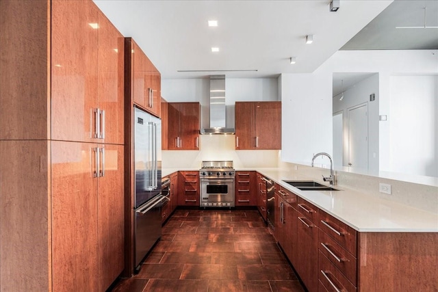 kitchen featuring high end appliances, wall chimney exhaust hood, kitchen peninsula, and sink