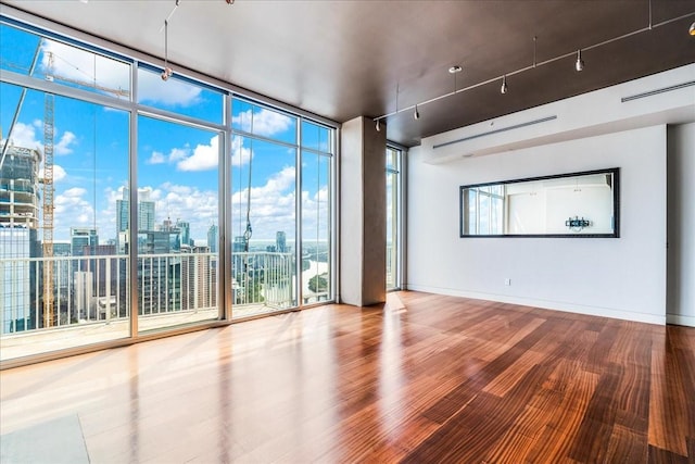 spare room with hardwood / wood-style flooring, plenty of natural light, and a wall of windows