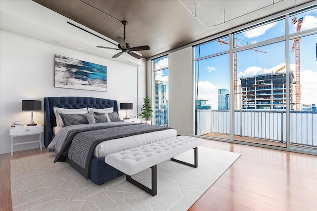 bedroom featuring ceiling fan, expansive windows, access to exterior, and light hardwood / wood-style floors