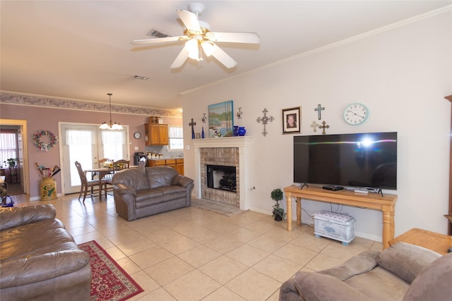 tiled living room featuring crown molding, a fireplace, and ceiling fan with notable chandelier