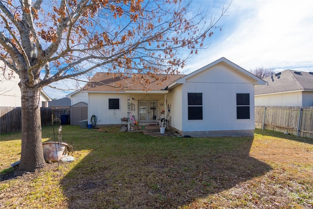 back of house featuring a lawn and a storage shed