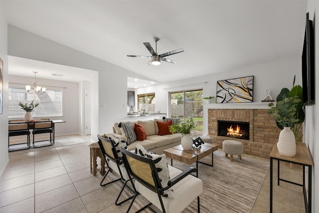 tiled living room featuring ceiling fan with notable chandelier, lofted ceiling, and a fireplace