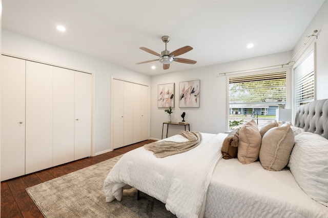 bedroom with ceiling fan, multiple closets, and dark hardwood / wood-style floors