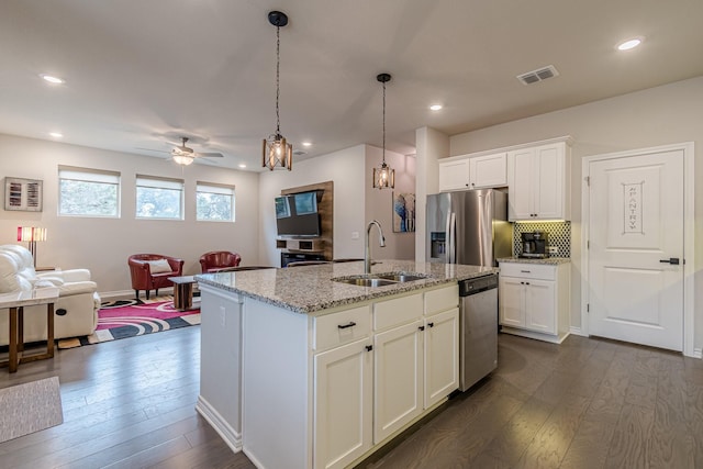 kitchen with a center island with sink, sink, white cabinetry, light stone countertops, and stainless steel appliances