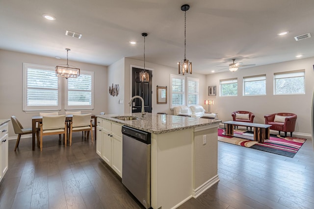 kitchen with a center island with sink, stainless steel dishwasher, sink, hanging light fixtures, and light stone countertops