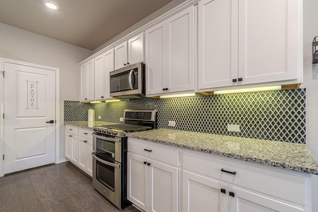 kitchen featuring appliances with stainless steel finishes, dark wood-type flooring, white cabinetry, backsplash, and light stone counters