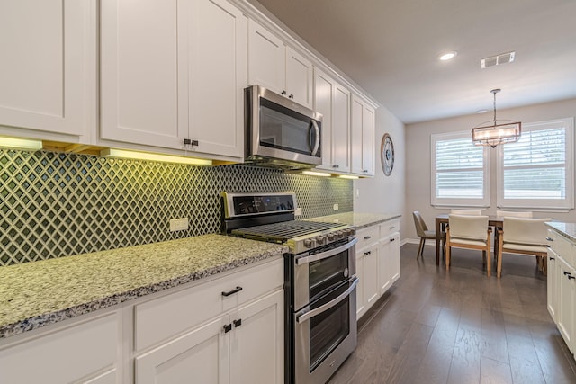 kitchen with decorative light fixtures, white cabinets, appliances with stainless steel finishes, and dark hardwood / wood-style flooring