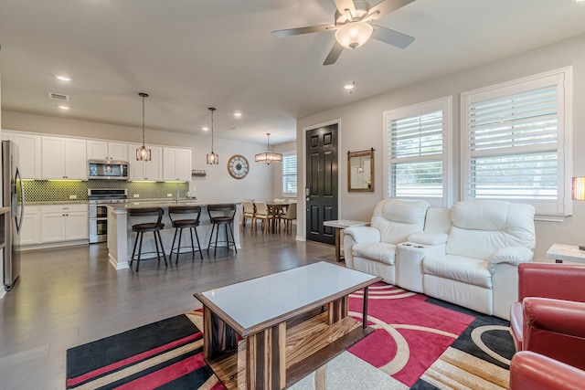 living room featuring dark hardwood / wood-style flooring and ceiling fan with notable chandelier