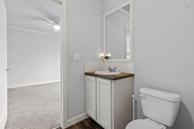 bathroom featuring toilet, ceiling fan, ornamental molding, and vanity