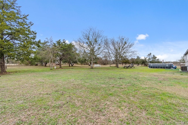 view of yard featuring central AC unit and a pool