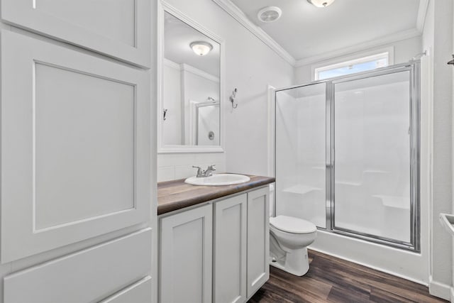 bathroom with hardwood / wood-style floors, a shower with door, vanity, toilet, and crown molding