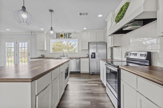 kitchen with premium range hood, a center island, white cabinetry, appliances with stainless steel finishes, and wood counters