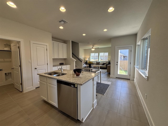 kitchen featuring stainless steel dishwasher, white cabinets, a kitchen island with sink, and sink