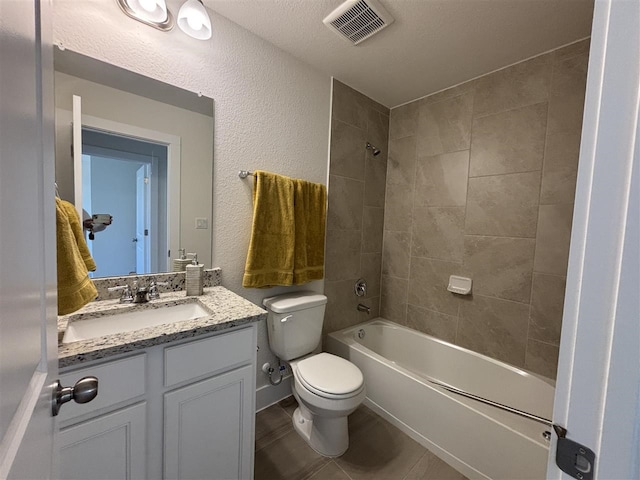 full bathroom with toilet, tiled shower / bath, vanity, and a textured ceiling