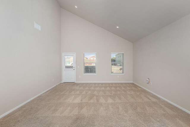 carpeted empty room with high vaulted ceiling and a healthy amount of sunlight