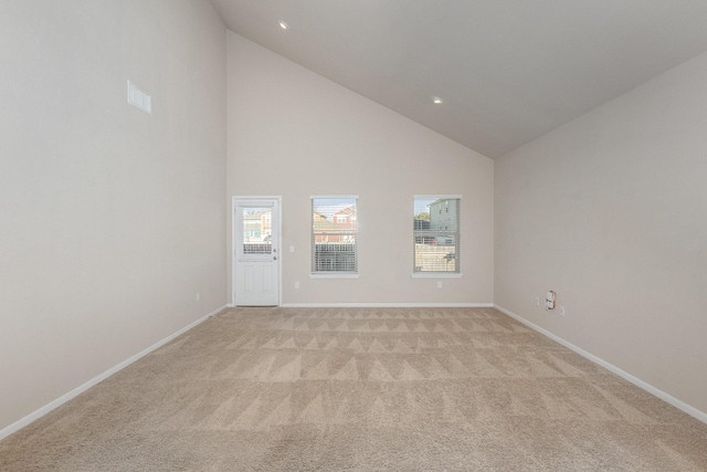 spare room featuring a wealth of natural light, light colored carpet, and high vaulted ceiling