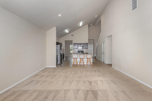 unfurnished living room featuring light carpet and high vaulted ceiling