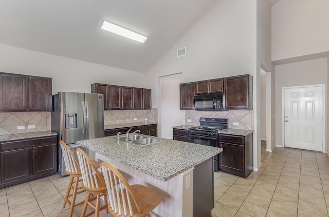 kitchen featuring a breakfast bar, a kitchen island with sink, high vaulted ceiling, and black appliances