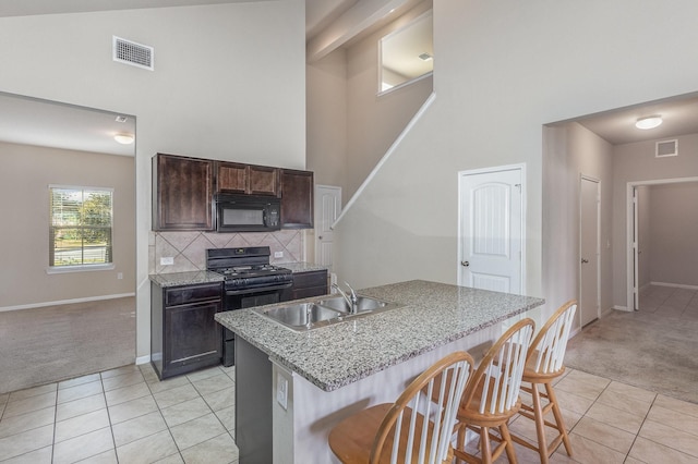 kitchen featuring sink, black appliances, light carpet, a kitchen island with sink, and backsplash