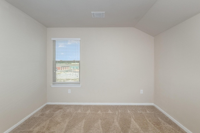 empty room with vaulted ceiling and carpet flooring