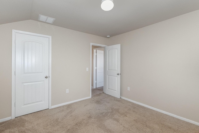 unfurnished bedroom featuring vaulted ceiling, light carpet, and a closet