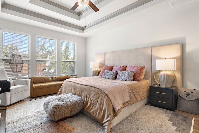 bedroom with a raised ceiling, ceiling fan, crown molding, and wood-type flooring