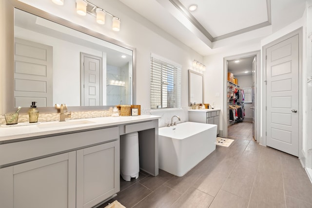 bathroom with a tray ceiling, vanity, ornamental molding, and independent shower and bath