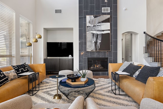 living room featuring hardwood / wood-style flooring, radiator heating unit, a tile fireplace, and a high ceiling