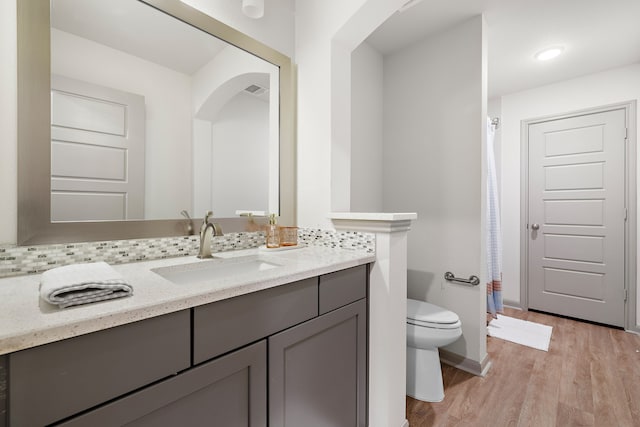 bathroom featuring tasteful backsplash, vanity, wood-type flooring, and toilet