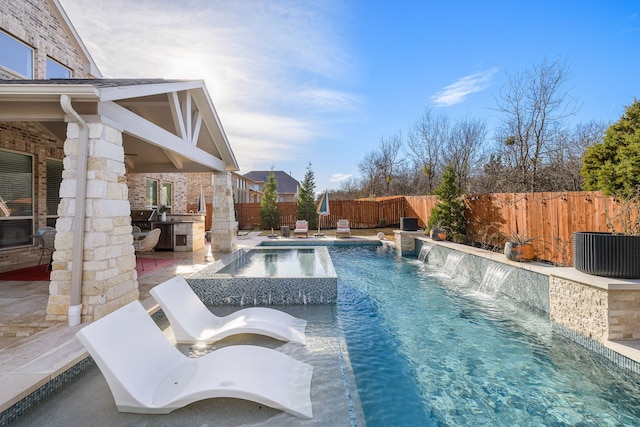 view of pool featuring exterior kitchen, an in ground hot tub, pool water feature, and a patio