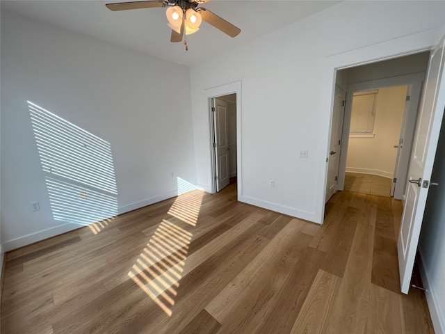 unfurnished bedroom with light wood-type flooring, ceiling fan, and a spacious closet