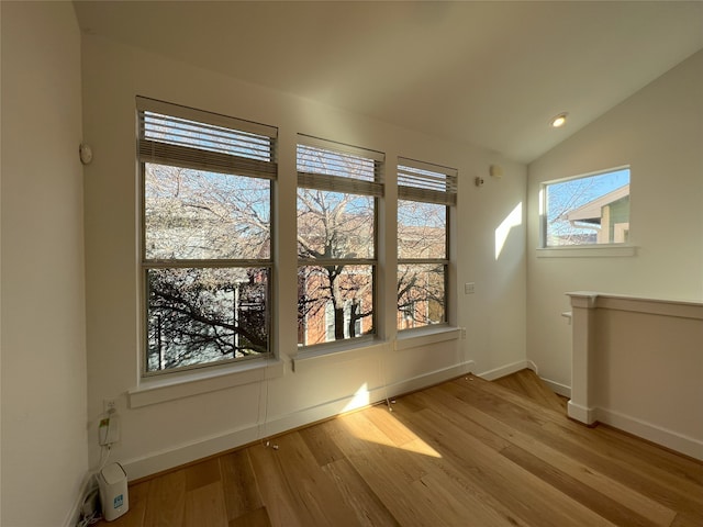 spare room with light hardwood / wood-style floors and lofted ceiling