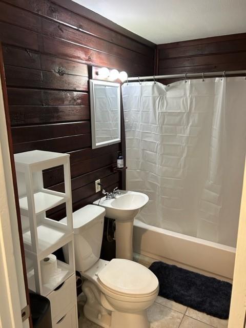 bathroom with toilet, wood walls, shower / tub combo, and tile patterned flooring