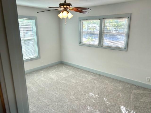 carpeted spare room featuring ceiling fan