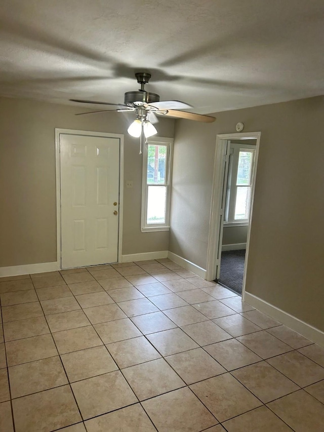 foyer featuring a wealth of natural light, light tile patterned floors, and ceiling fan