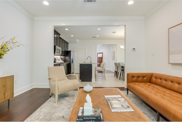 living room featuring dark wood-type flooring, crown molding, and sink