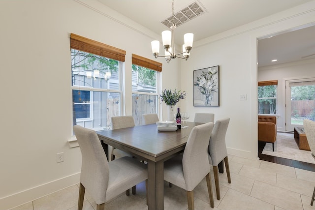 tiled dining area with crown molding and a chandelier