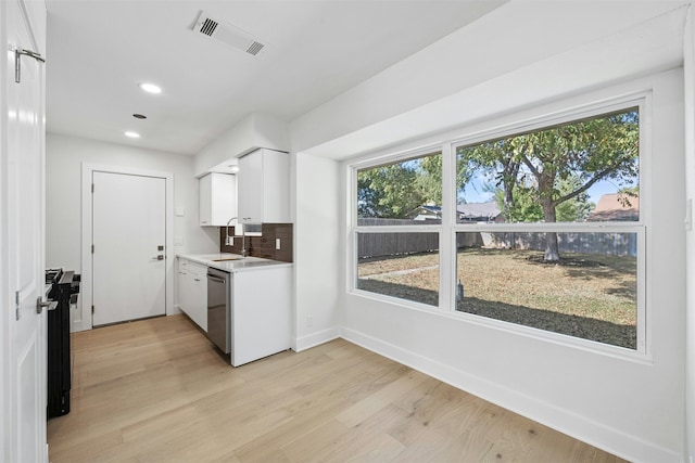 kitchen with white cabinets, backsplash, dishwasher, and light hardwood / wood-style flooring